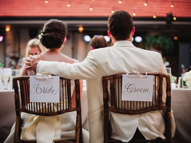 bride and groom sit in custom chairs