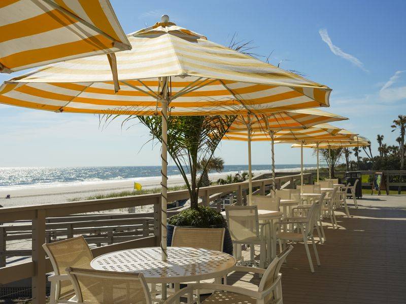 tables with umbrellas on a deck overlooking the ocean
