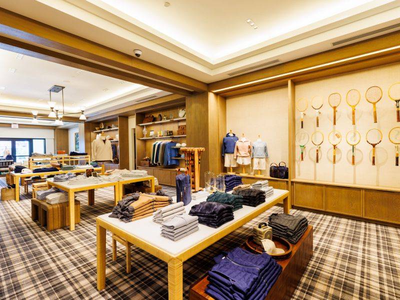 an brightly lit room with raquets on the wall and clothing on tables