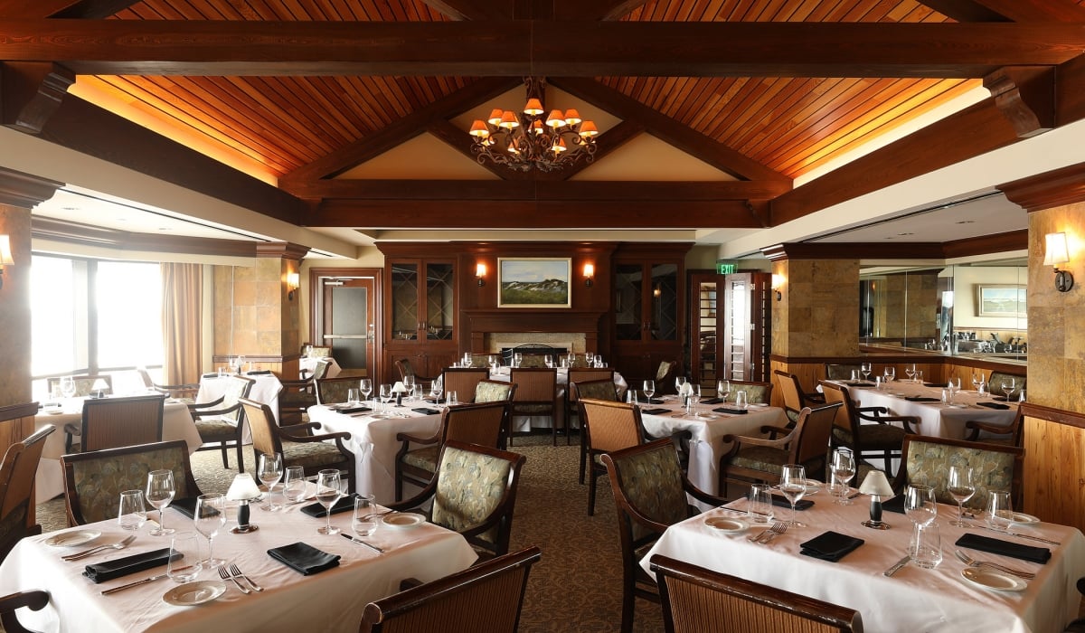 Set tables in a restaurant with a high, wood paneled ceiling