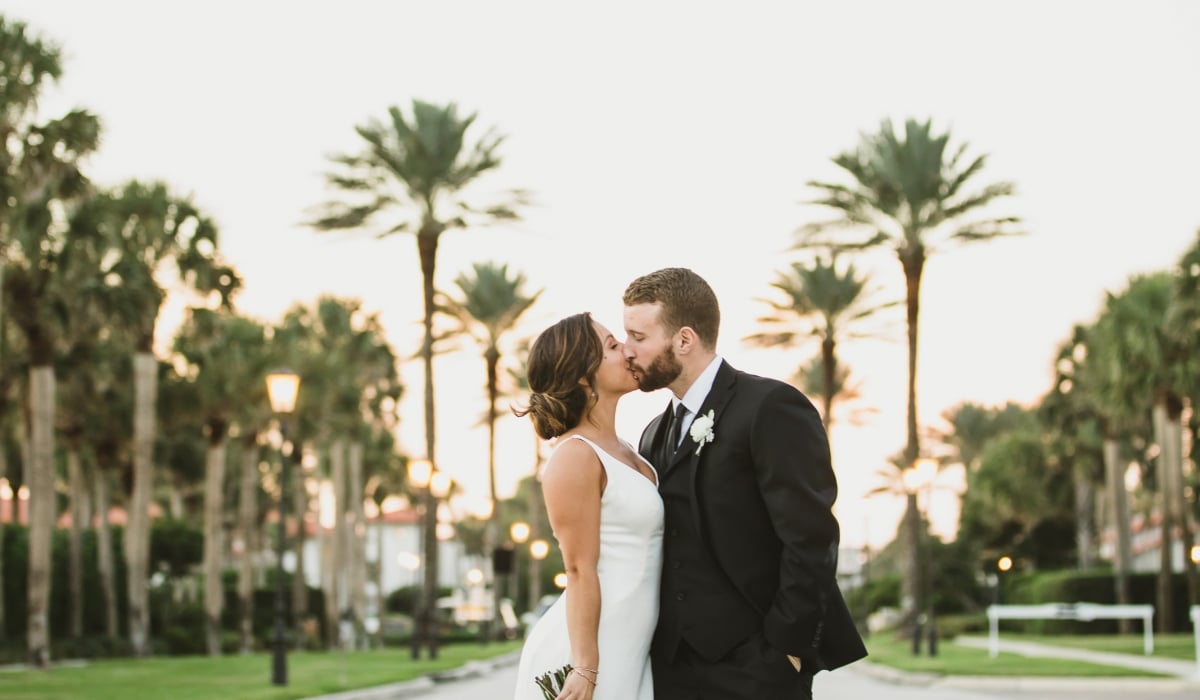 Framed by palms, a bride at groom kiss at Ponte Vedra Inn & Club. 