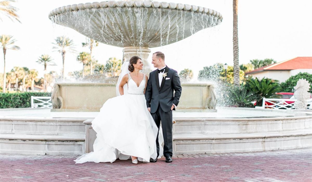 A smiling bride and groom stand in front of the famous fountain at Ponte Vedra Inn & Club.