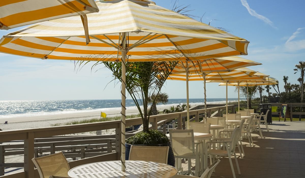 tables with umbrellas on a deck overlooking the ocean