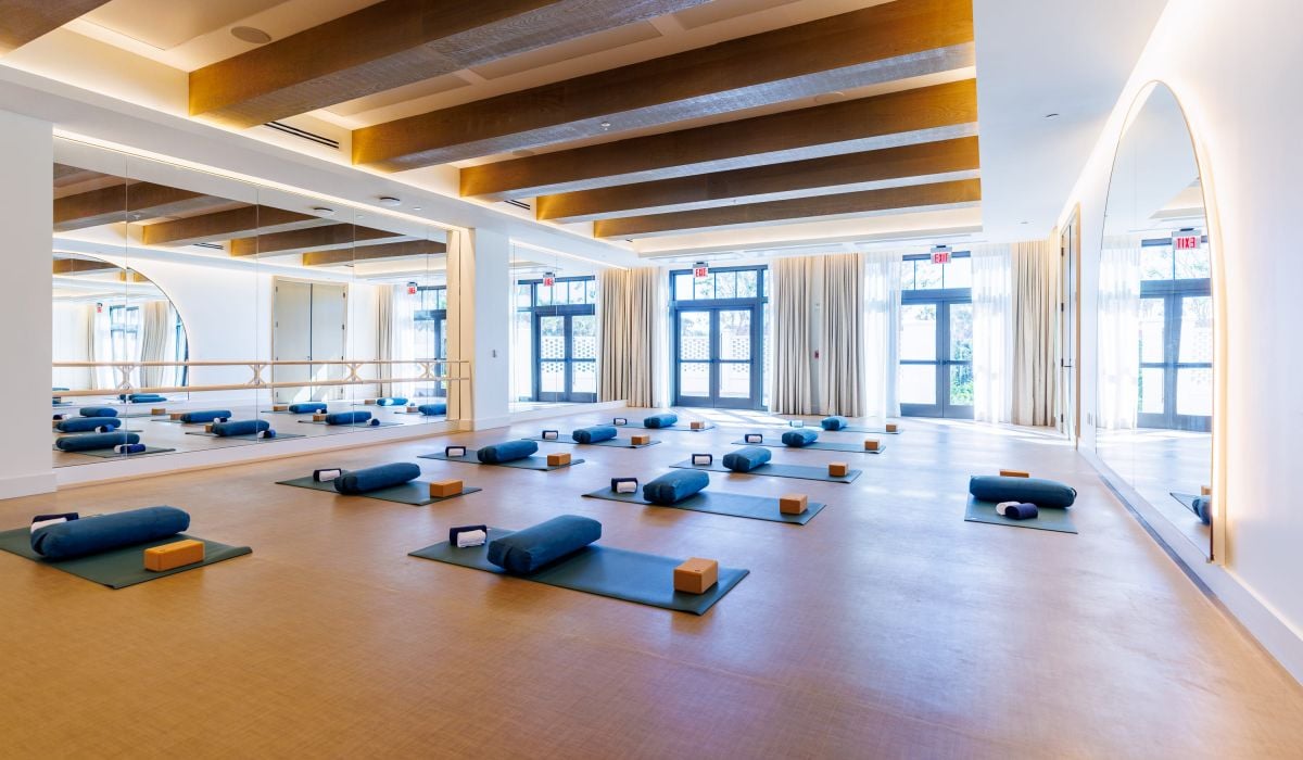 a fitness area surrounded by floor to ceiling windows and wooden beams on the ceiling