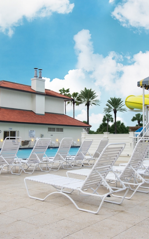 Lounging chairs along the kid's pool with a yellow water slide in the background