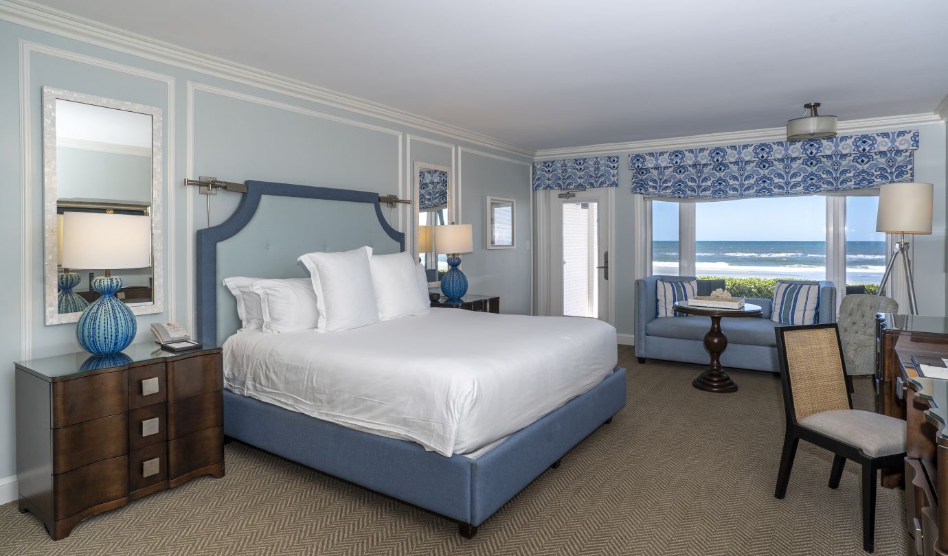 guest room with a bed, nightstand and large windows