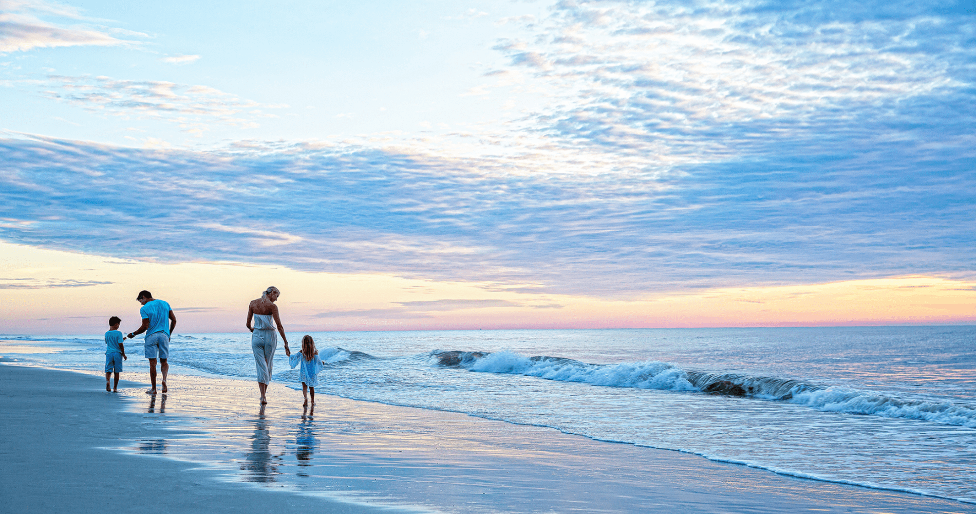 Family walking beach at sunset