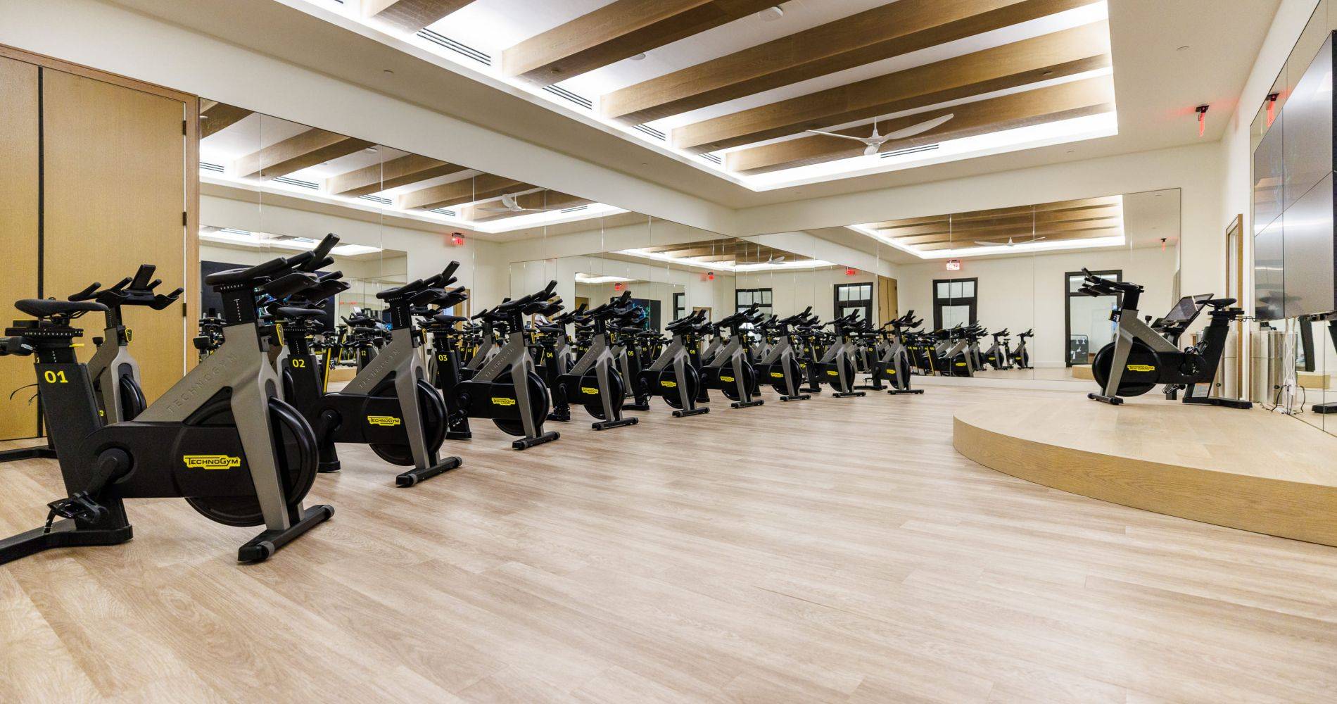a brightly lit cycling room with a row of bikes and one on a stage