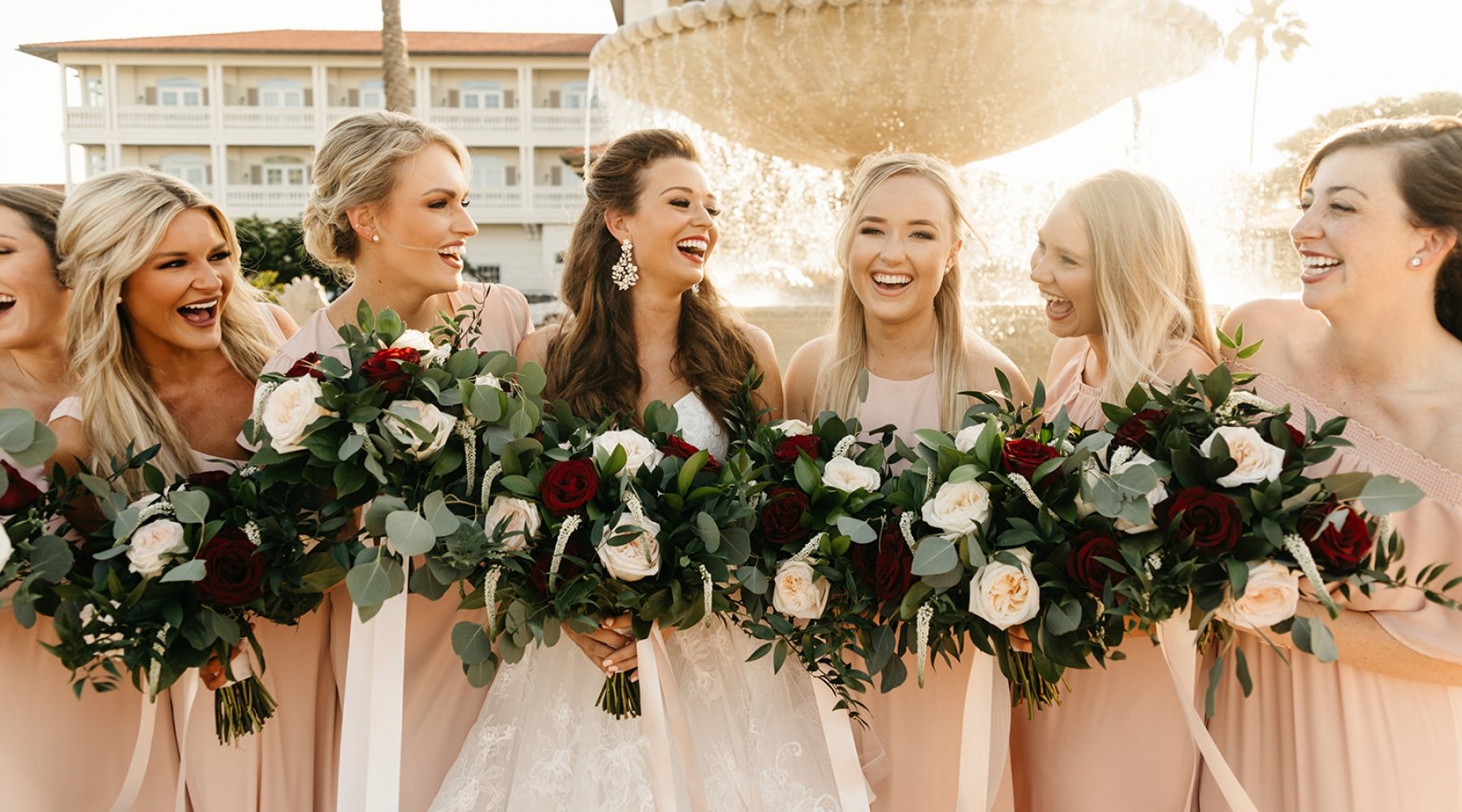 bride and bridesmaids pose in front of fountain