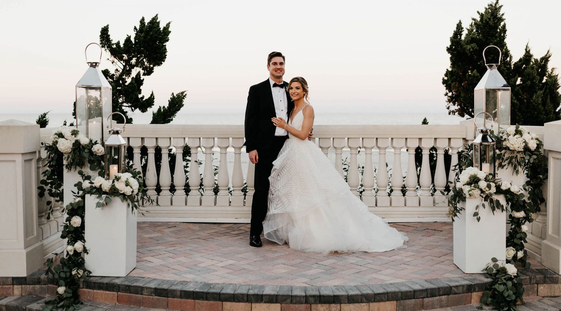 A bride and groom stand surrounded by flowers and the oceanfront courtyard at Ponte Vedra Inn & Club.